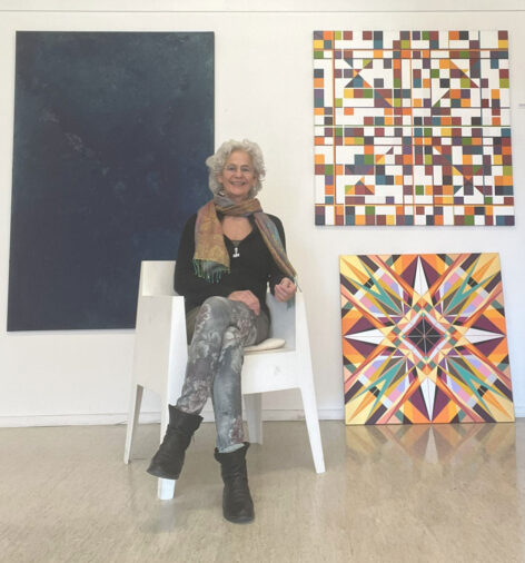 homepage-about-me woman sitting beside two geometric healing paintings